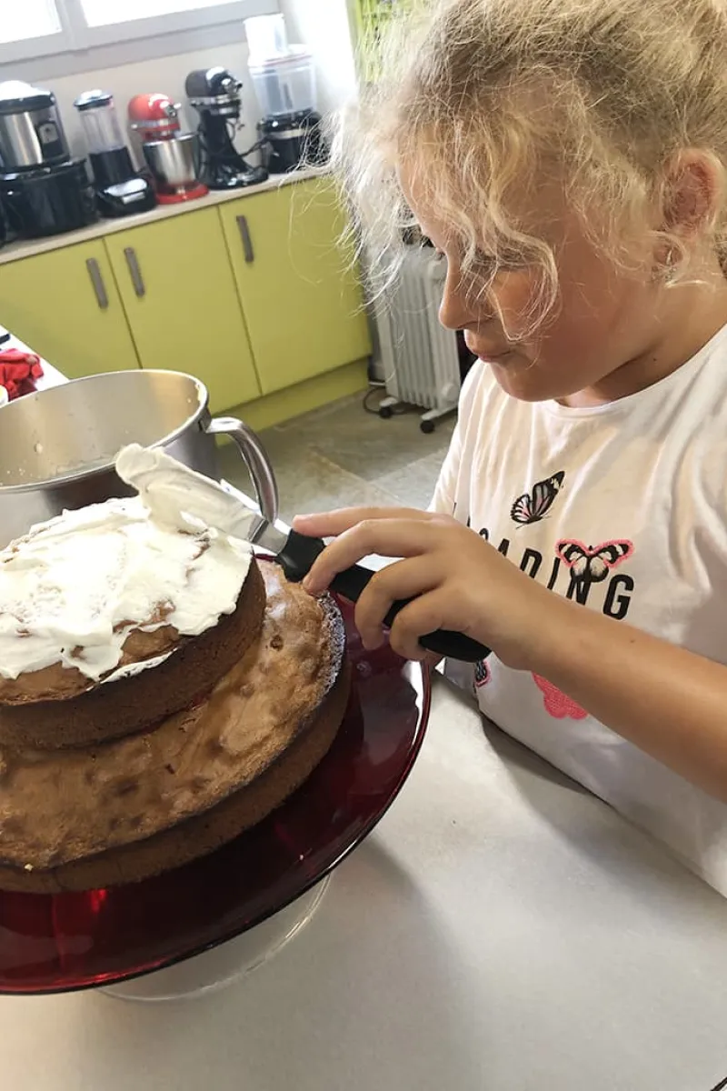 Nichtje Tessel ‘plakt’ de cakes vast met slagroom.