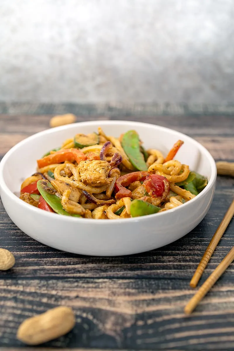 Udon noedels met kip en groenten in een pindasaus