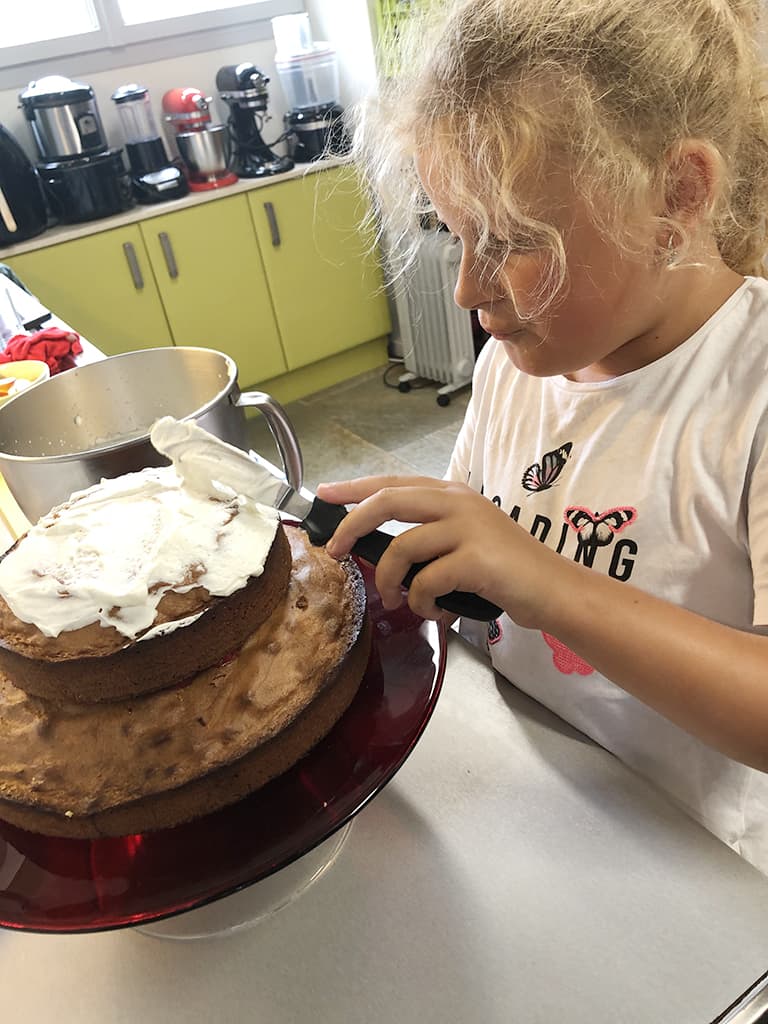 Nichtje Tessel ‘plakt’ de cakes vast met slagroom.